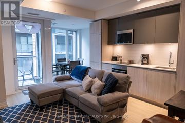 Toronto (Victoria Village) condo for rent - A modern living room with a grey couch and a black and white checkered rug.