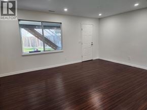 Pitt Meadows apartment for rent - A room with wooden flooring and a window showing an outdoor staircase.