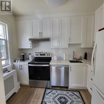 Toronto (Leaside) apartment for rent - A kitchen with white cabinets and a black stove top oven.