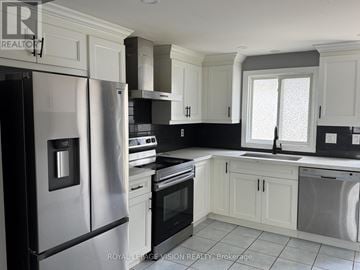 Barrie (Grove East) apartment for rent - A kitchen with white cabinets and a black refrigerator.