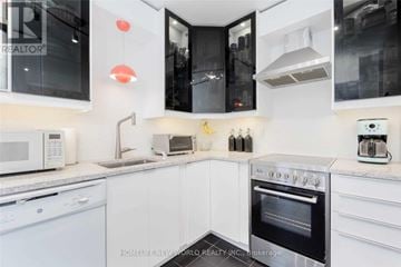 Toronto (Bay Street Corridor) condo for rent - A modern kitchen with white cabinets and black appliances.