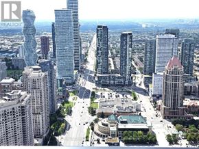 Mississauga (City Centre) condo for rent - A cityscape with a mix of modern and older buildings, a large open square, and a clear sky.