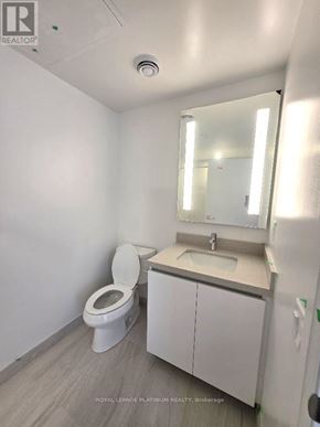 Mississauga (City Centre) condo for rent - A white bathroom with a toilet, sink, and mirror.