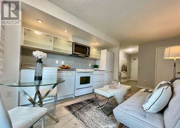Toronto (Waterfront Communities) condo for rent - A modern kitchen with a glass table and white chairs.