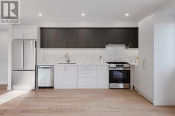 Toronto (Danforth) multi-family for rent - A modern kitchen with white cabinets and a stainless steel refrigerator.