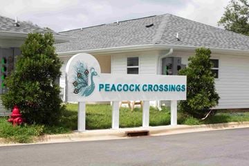 Pensacola apartment for rent - A sign that says Peacock Crossings stands in front of a house.