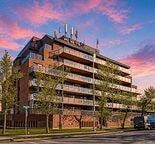 Calgary apartment for rent - A large apartment building with balconies and a parking lot in front.