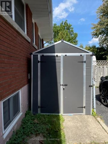 Hamilton (Huntington) apartment for rent - A small grey shed sits in front of a red brick house.