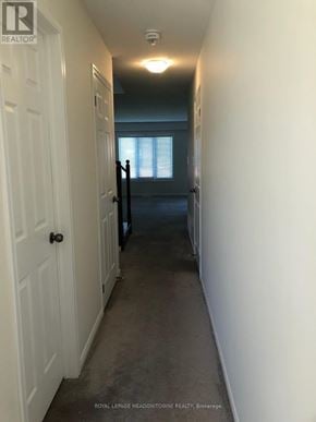 Brantford townhouse for rent - A hallway with a door on the left and a window with blinds on the right.