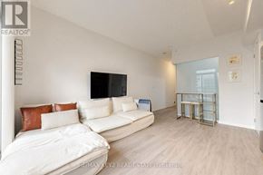 Toronto (Little Portugal) condo for rent - A living room with a white couch and a television on the wall.