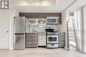 Toronto (Little Portugal) condo for rent - A modern kitchen with a refrigerator, oven, microwave, and cabinets.