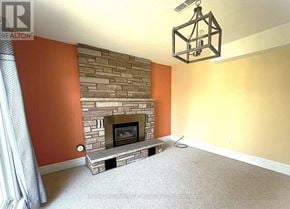 Oshawa (Vanier) apartment for rent - A living room with a stone fireplace and a hanging light fixture.
