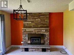 Oshawa (Vanier) apartment for rent - A stone fireplace with a hanging light fixture above it.