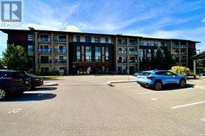 Guelph (Pineridge/Westminster Woods) condo for rent - A parking lot with cars and a building in the background.