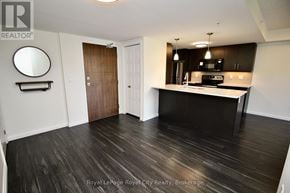 Guelph (Pineridge/Westminster Woods) condo for rent - A room with a wooden floor and a kitchen area with a microwave and oven.