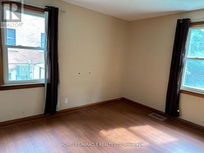 Waterloo apartment for rent - A room with wooden floors and two windows with curtains.