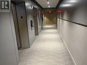 Toronto (Church-Yonge Corridor) condo for rent - A long hallway with elevators on the left and a red exit sign on the wall.