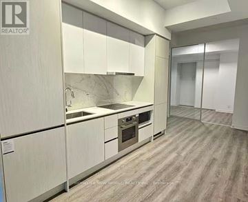 Toronto (Moss Park) condo for rent - A modern kitchen with white cabinets and a marble backsplash.