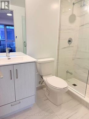 Toronto (Moss Park) condo for rent - A white toilet in a bathroom with a glass shower stall.