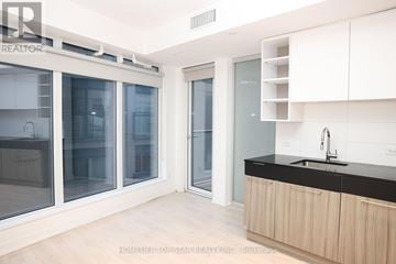 Toronto (Church-Yonge Corridor) condo for rent - A modern kitchen with white cabinets and a black countertop.