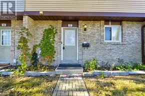 Brampton (Madoc) townhouse for rent - A house with a grey front door and a small front yard.