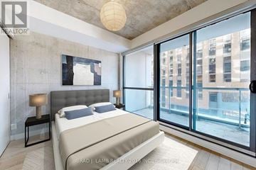Toronto (Waterfront Communities) condo for rent - A bedroom with a large bed and a view of the city.