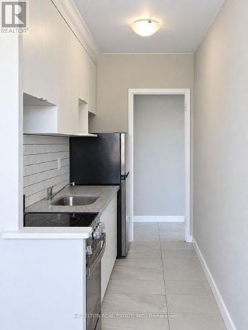 Toronto (Annex) condo for rent - A kitchen with white cabinets and a black refrigerator.
