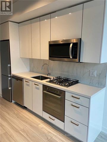 Toronto (Waterfront Communities) condo for rent - A modern kitchen with white cabinets and a black fridge.
