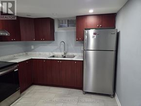 Brampton (Toronto Gore Rural Estate) apartment for rent - A kitchen with a stainless steel refrigerator and wooden cabinets.