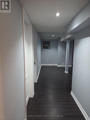 Brampton (Toronto Gore Rural Estate) apartment for rent - A long hallway with black tile flooring and white walls.