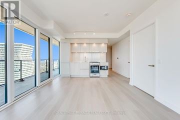 Mississauga (City Centre) condo for rent - A spacious, well-lit living room with a kitchenette in the background.