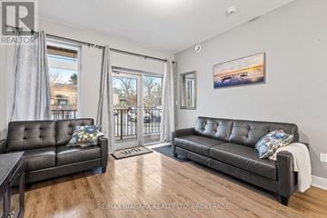 Niagara Falls (Chippawa) condo for rent - A living room with a black leather sofa and a painting on the wall.