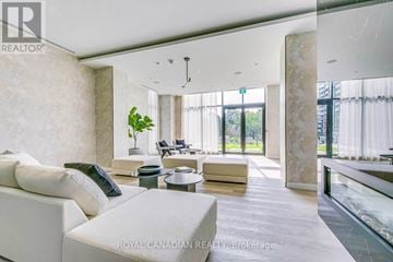 Mississauga (Cooksville) condo for rent - A spacious living room with a white sofa set and a glass display cabinet.