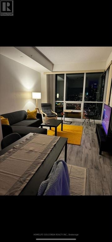 Toronto (Mimico) condo for rent - A modern living room with a black couch and a large window overlooking the city.