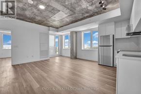 Ottawa apartment for rent - A spacious, empty room with wooden floors and a concrete ceiling.