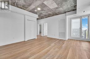 Ottawa apartment for rent - A realtor photo of a large empty room with wood floors and a concrete ceiling.