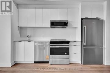 Ottawa apartment for rent - A modern kitchen with white cabinets and stainless steel appliances.