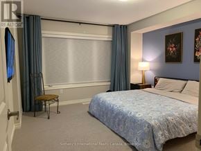 Collingwood townhouse for rent - A bedroom with a bed, chair, and window.