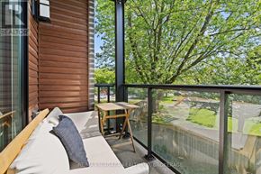 St. Catharines (Lakeport) condo for rent - A balcony with a table and chairs overlooking a green yard.