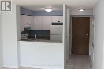 Toronto (Woburn) condo for rent - A kitchen with white cabinets and a brown door.