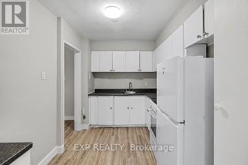 Ottawa condo for rent - A kitchen with white cabinets and a black countertop.