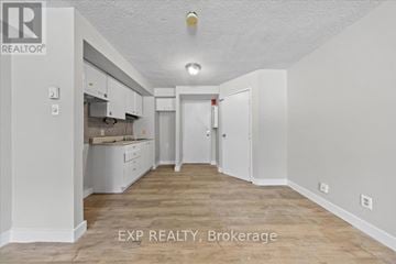 Ottawa condo for rent - A white room with a kitchen area and a brokerage sign.