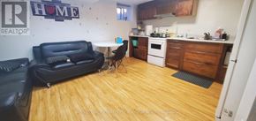 Toronto (Woodbine-Lumsden) apartment for rent - A black couch sits in a kitchen with wooden floors and white walls.