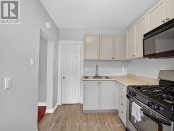 Toronto (The Beaches) multi-family for rent - A kitchen with white cabinets and a black stove top oven.