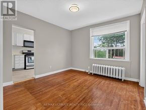 Toronto (The Beaches) multi-family for rent - A room with wooden floors and a window showing trees outside.