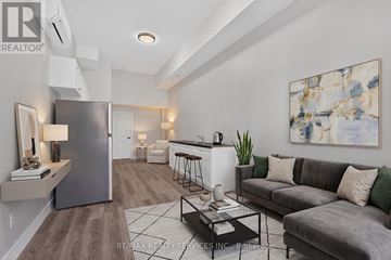 Welland (Welland Downtown) condo for rent - A modern living room with a grey couch and a large abstract painting on the wall.