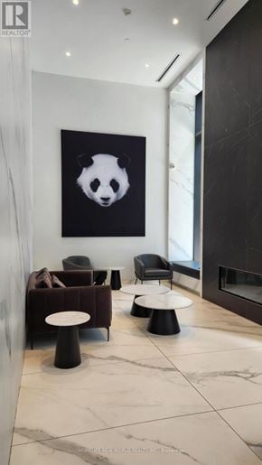 Toronto (Bay Street Corridor) condo for rent - A black and white panda painting hangs on a white wall above a dark brown couch.