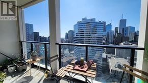 Toronto (Bay Street Corridor) condo for rent - A balcony with a table and chairs overlooking a cityscape.