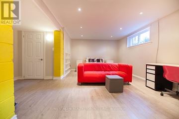 Toronto (Willowdale East) apartment for rent - A brightly colored living room with a red couch and a grey ottoman.