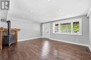 King (Schomberg) apartment for rent - A wood burning stove in a spacious room with hardwood floors and a large window.